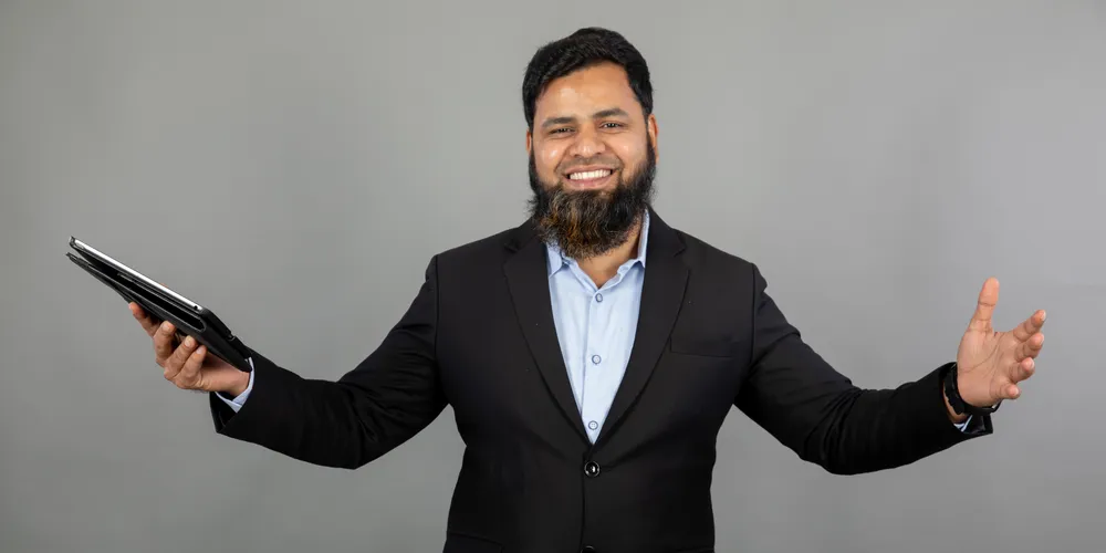 Abdul Lathif smiling, arms open, tablet in hand